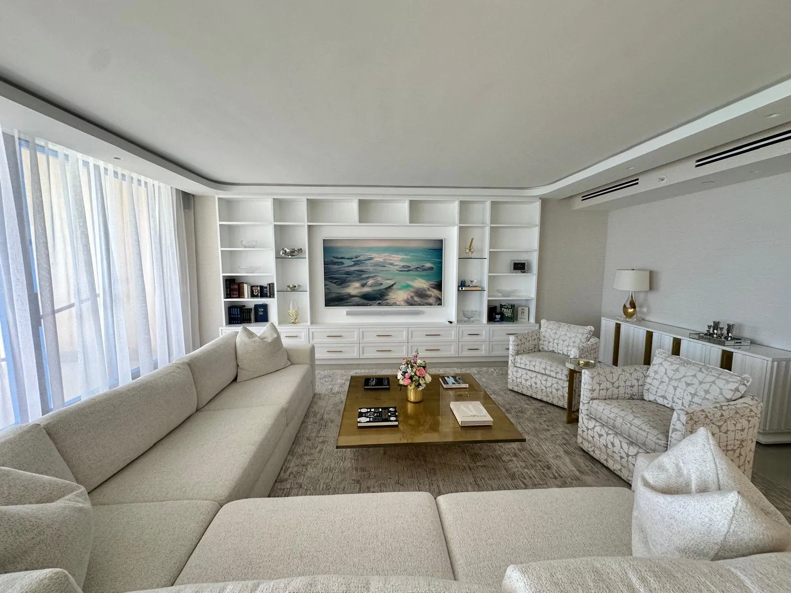 Wall-to-wall bookcase. White built-in across the whole wall, with a TV niche in the middle, open shelves and drawers below.